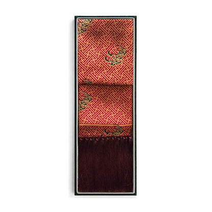 A folded red brocade shawl with gold geometric patterns and green floral accents, displayed in a thin black frame against a white background.